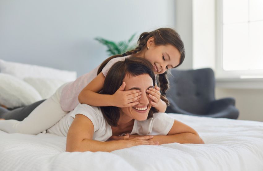Mom and daughter playing on bed